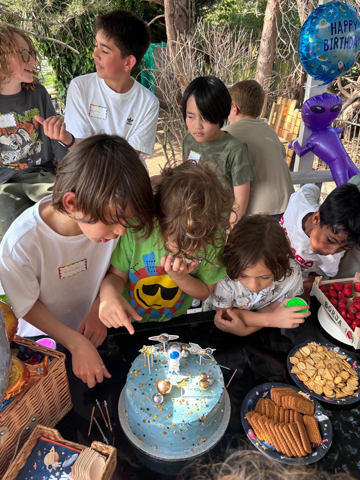Children gathered around a space-themed science birthday cake
